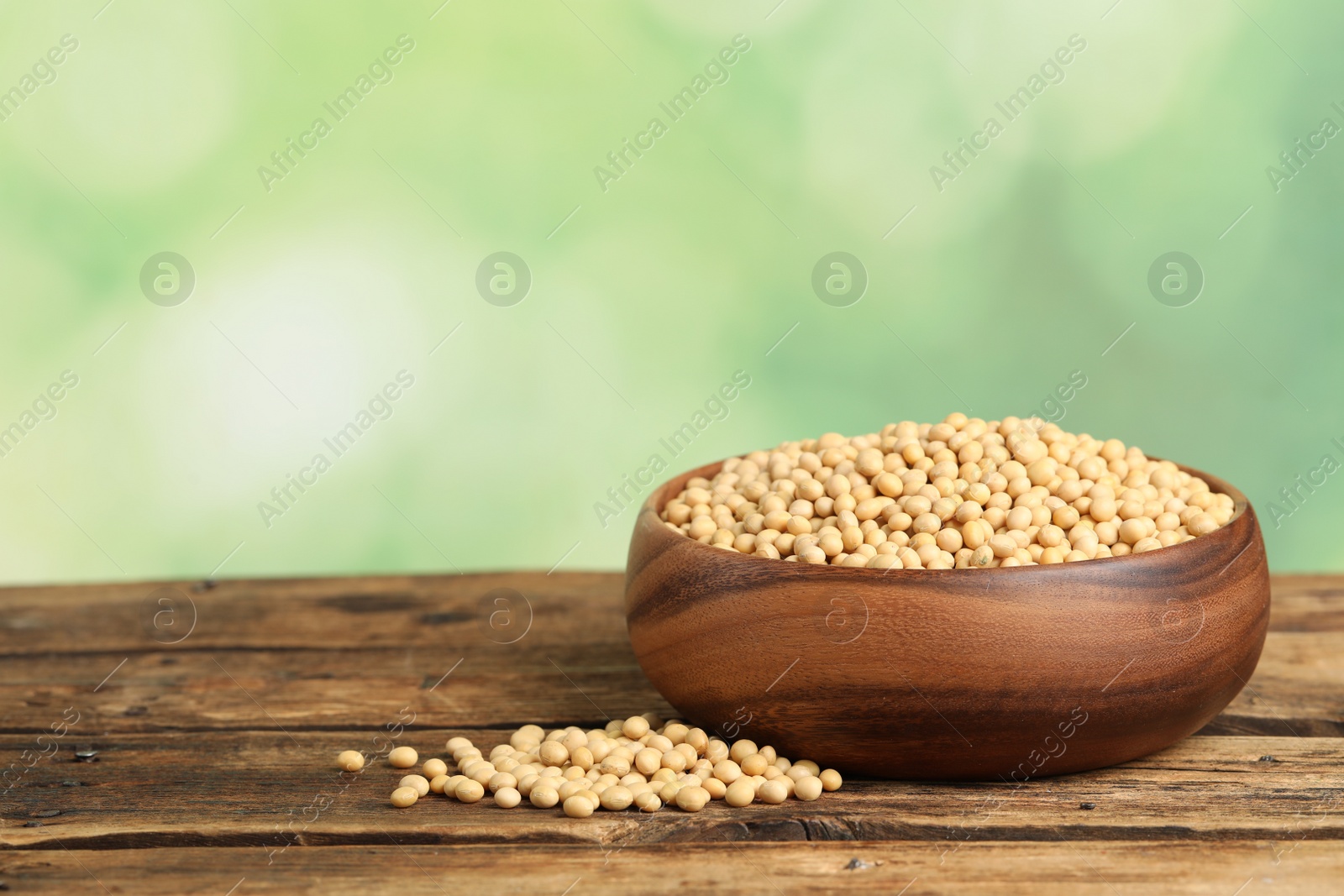 Photo of Natural soy beans on wooden table. Space for text