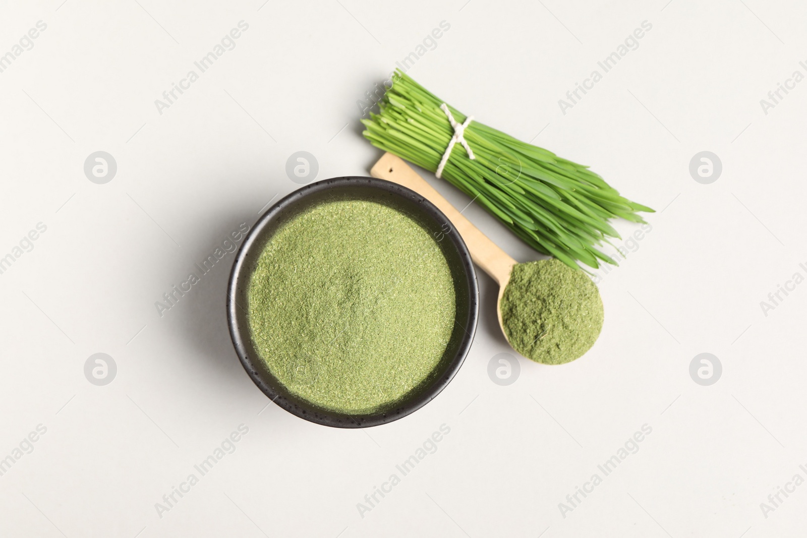 Photo of Wheat grass powder and fresh green sprouts on light table, flat lay