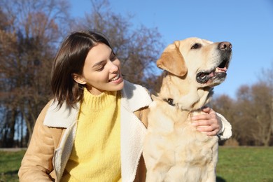 Beautiful young woman with cute Labrador Retriever on sunny day outdoors