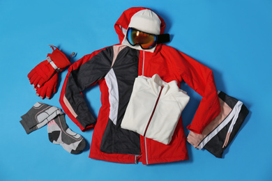 Photo of Stylish winter sport clothes on light blue background, flat lay