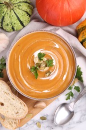 Photo of Delicious pumpkin soup served on white marble table, flat lay