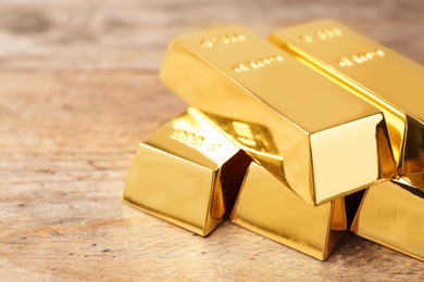 Photo of Precious shiny gold bars on wooden background