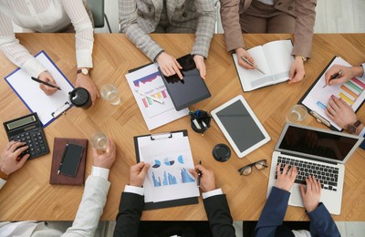 Photo of Businesspeople having meeting at table, top view. Management consulting