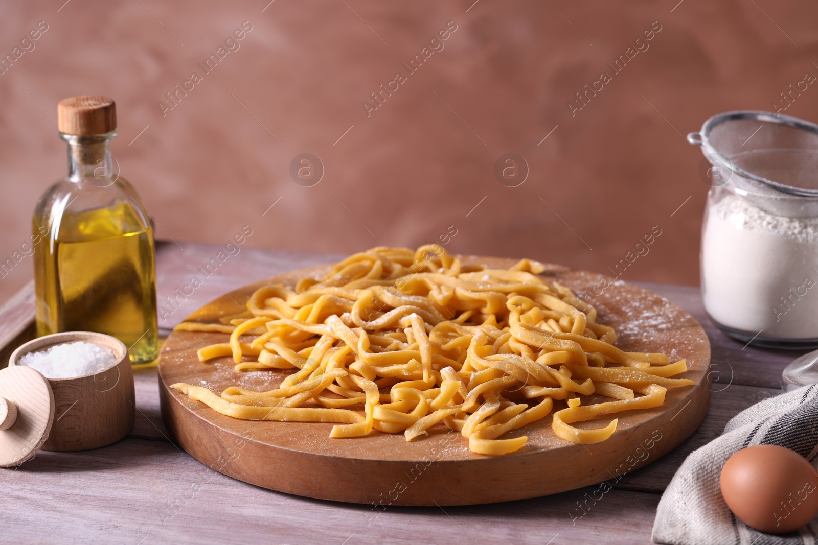 Photo of Board with homemade pasta, flour and ingredients on wooden table, space for text