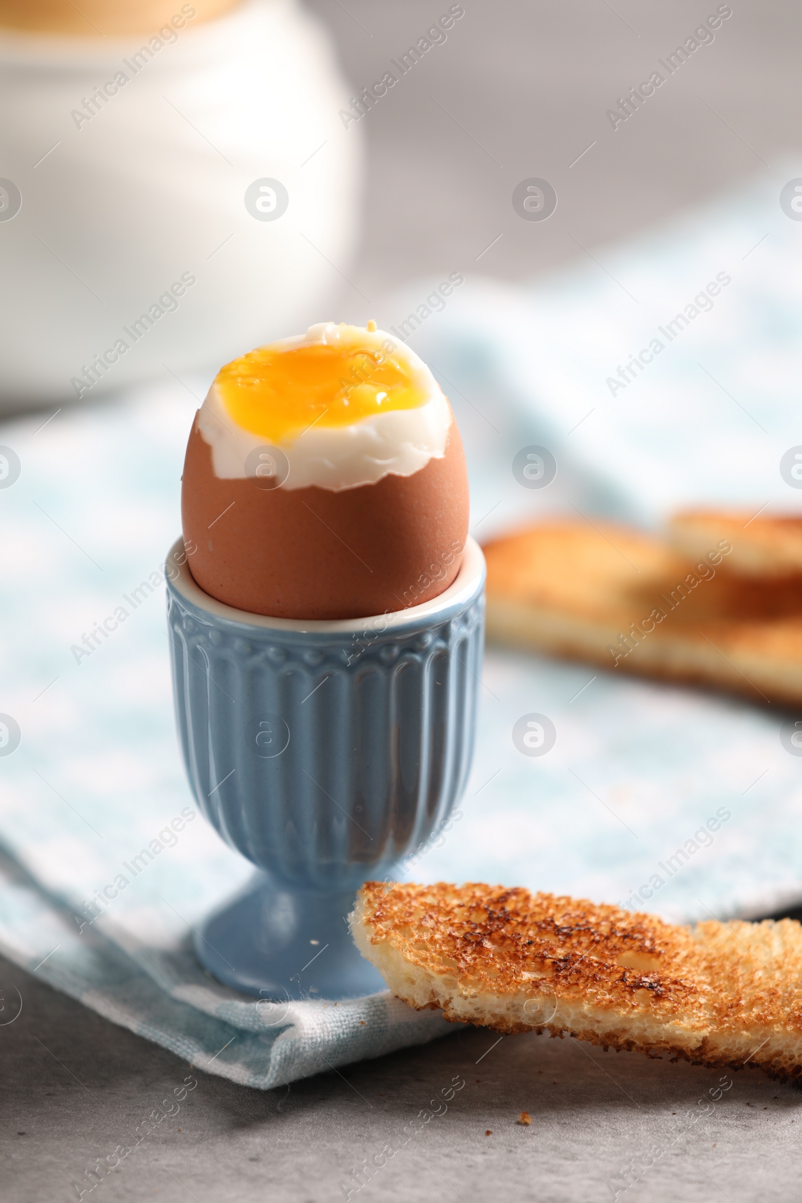 Photo of Tasty boiled chicken egg with toasted bread on grey table