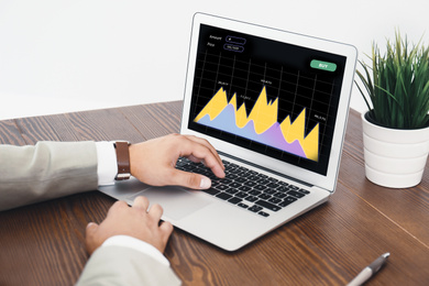 Image of  Broker working with laptop at table, closeup. Forex trading