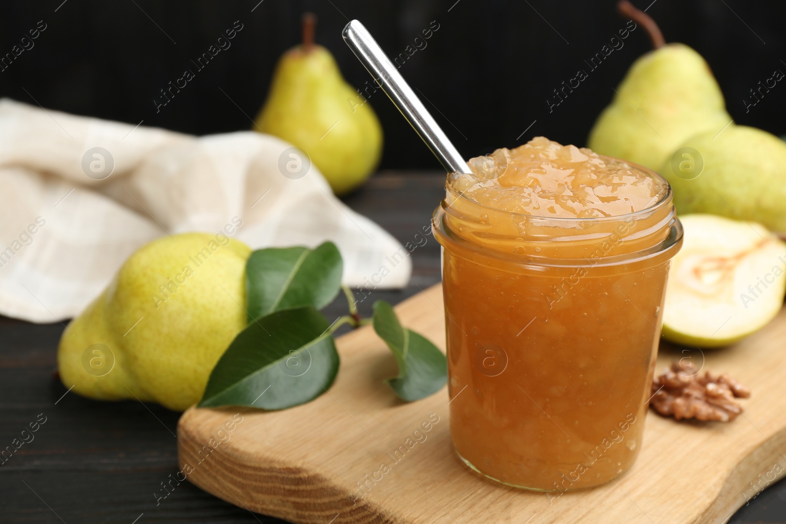 Photo of Delicious pear jam and fresh fruits on black table, closeup. Space for text