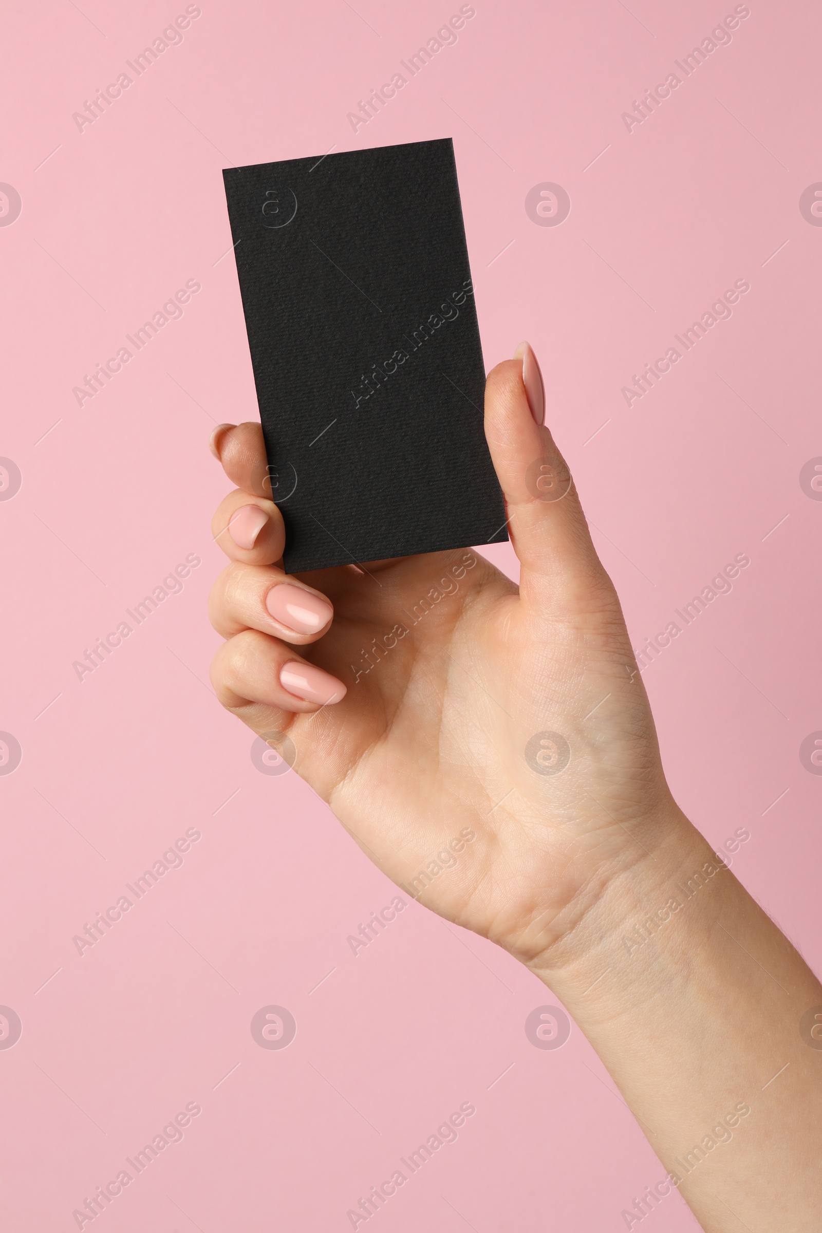 Photo of Woman with blank black business card on pink background, closeup. Mockup for design