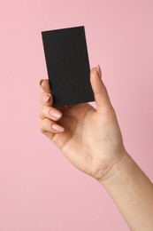 Photo of Woman with blank black business card on pink background, closeup. Mockup for design