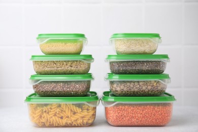 Plastic containers filled with food products on white table near tiled wall