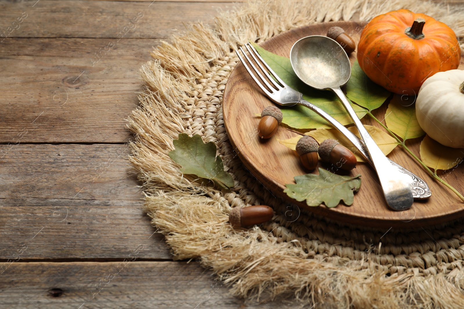 Photo of Autumn table setting with pumpkins and fallen leaves on wooden background, closeup. Space for text