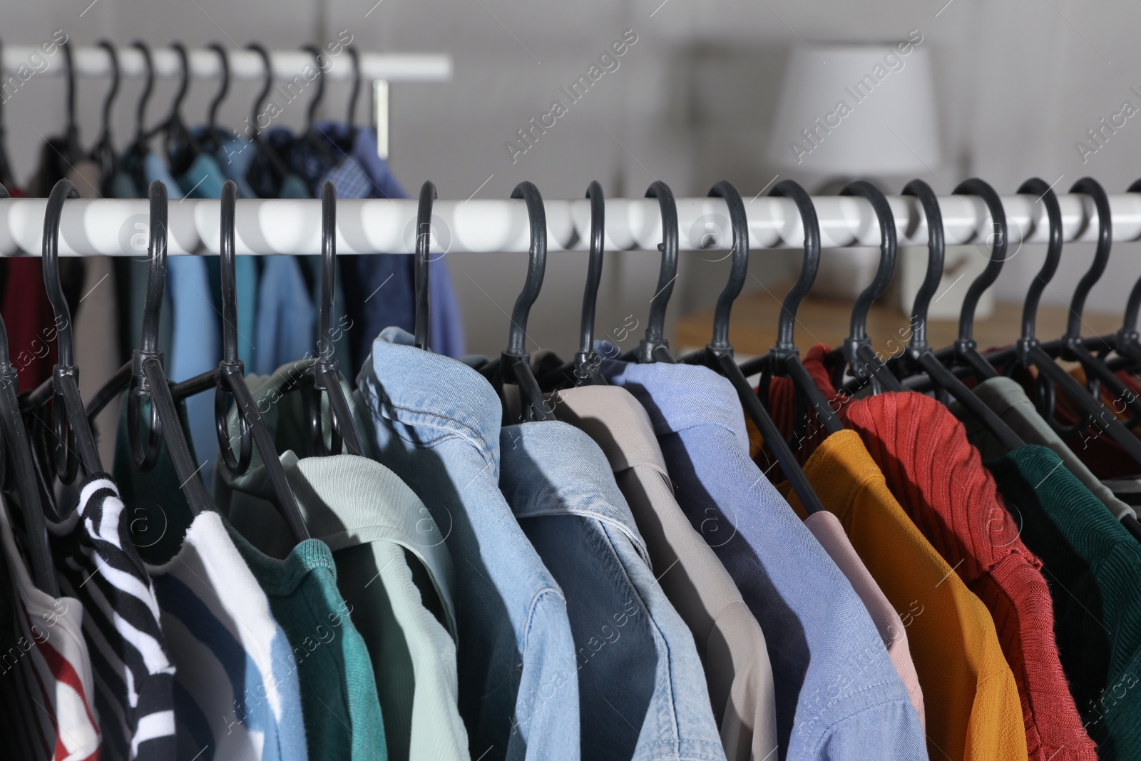 Photo of Rack with stylish clothes indoors, closeup. Fast fashion