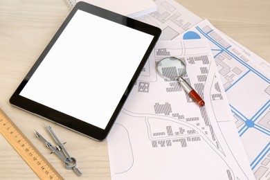 Photo of Office stationery, tablet and cadastral maps of territory with buildings on white wooden table