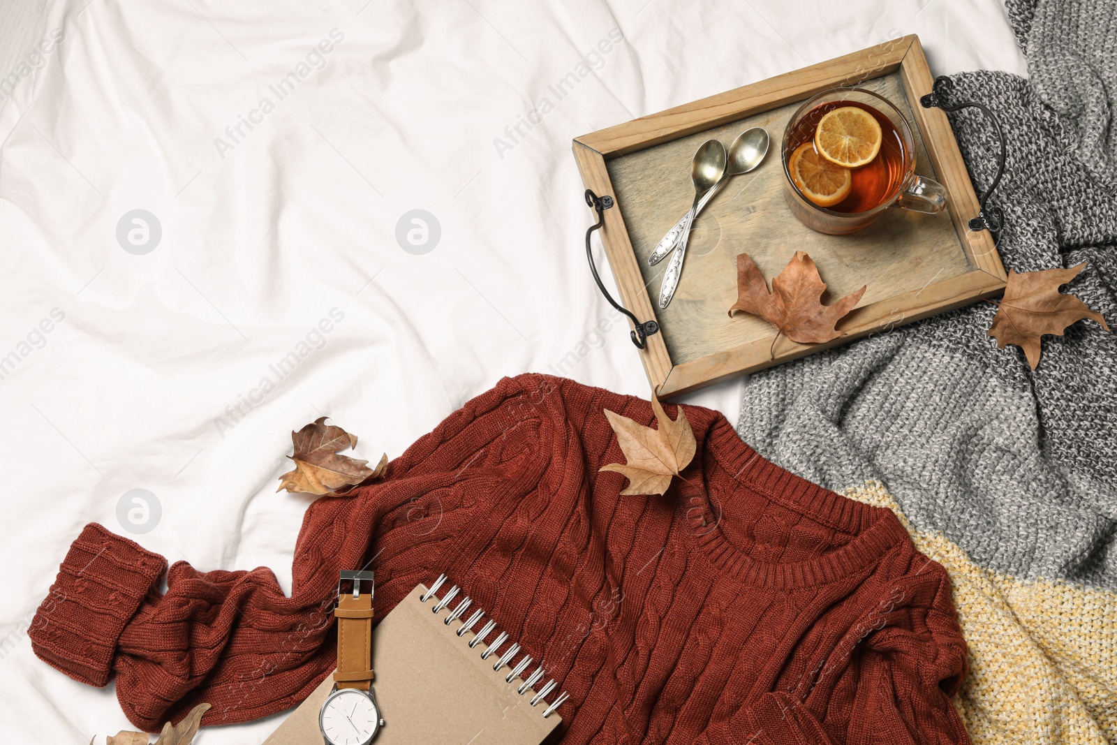 Photo of Flat lay composition with soft knitted sweater on white fabric