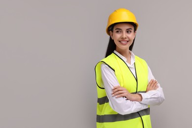 Engineer in hard hat on grey background, space for text
