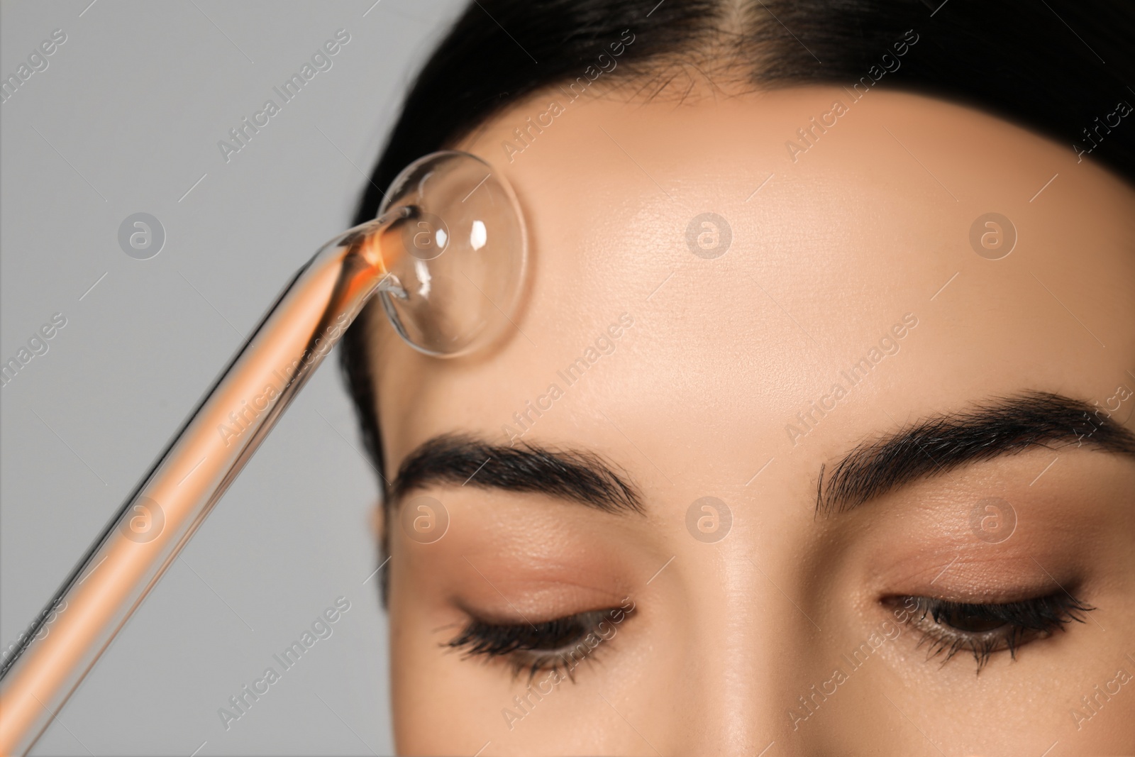 Photo of Woman using high frequency darsonval device on grey background, closeup