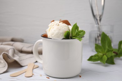 Photo of Scoopsice cream with caramel sauce, candies and mint leaves on white textured table, closeup