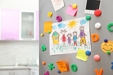 Sheets of paper, child's drawing and magnets on refrigerator door in kitchen. Space for text