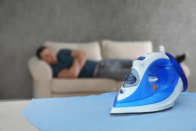 Modern iron and sleeping man in room. Space for text