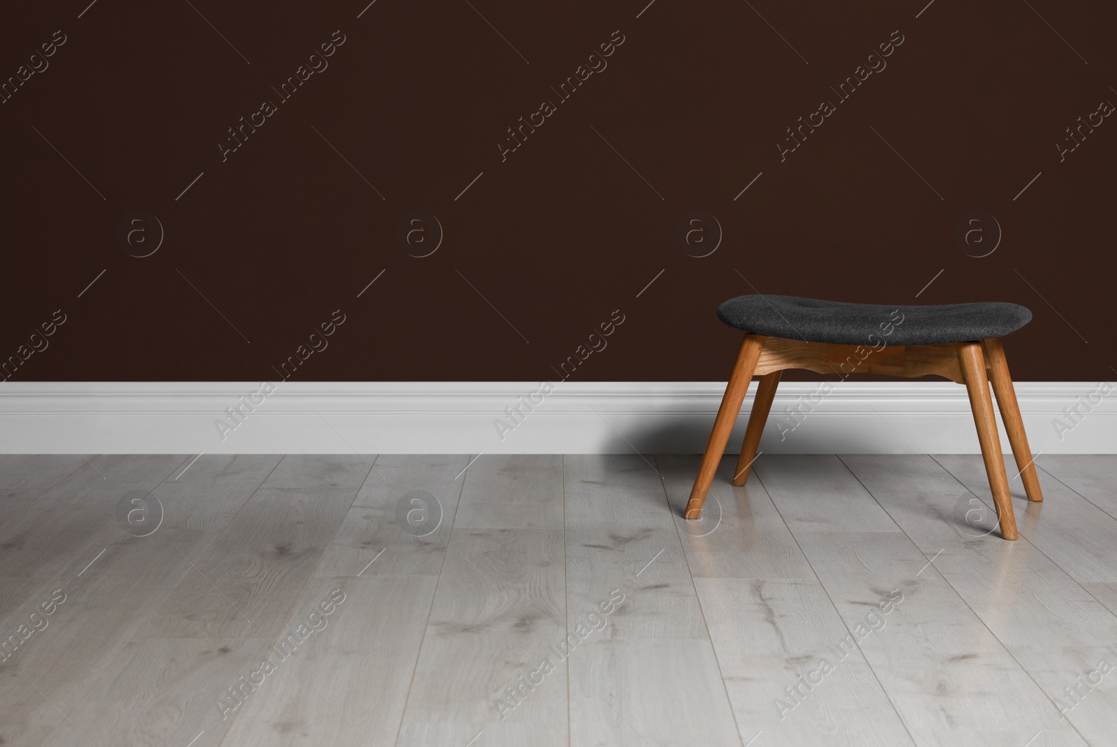 Photo of Stylish stool near brown wall indoors. Space for text