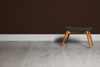 Photo of Stylish stool near brown wall indoors. Space for text