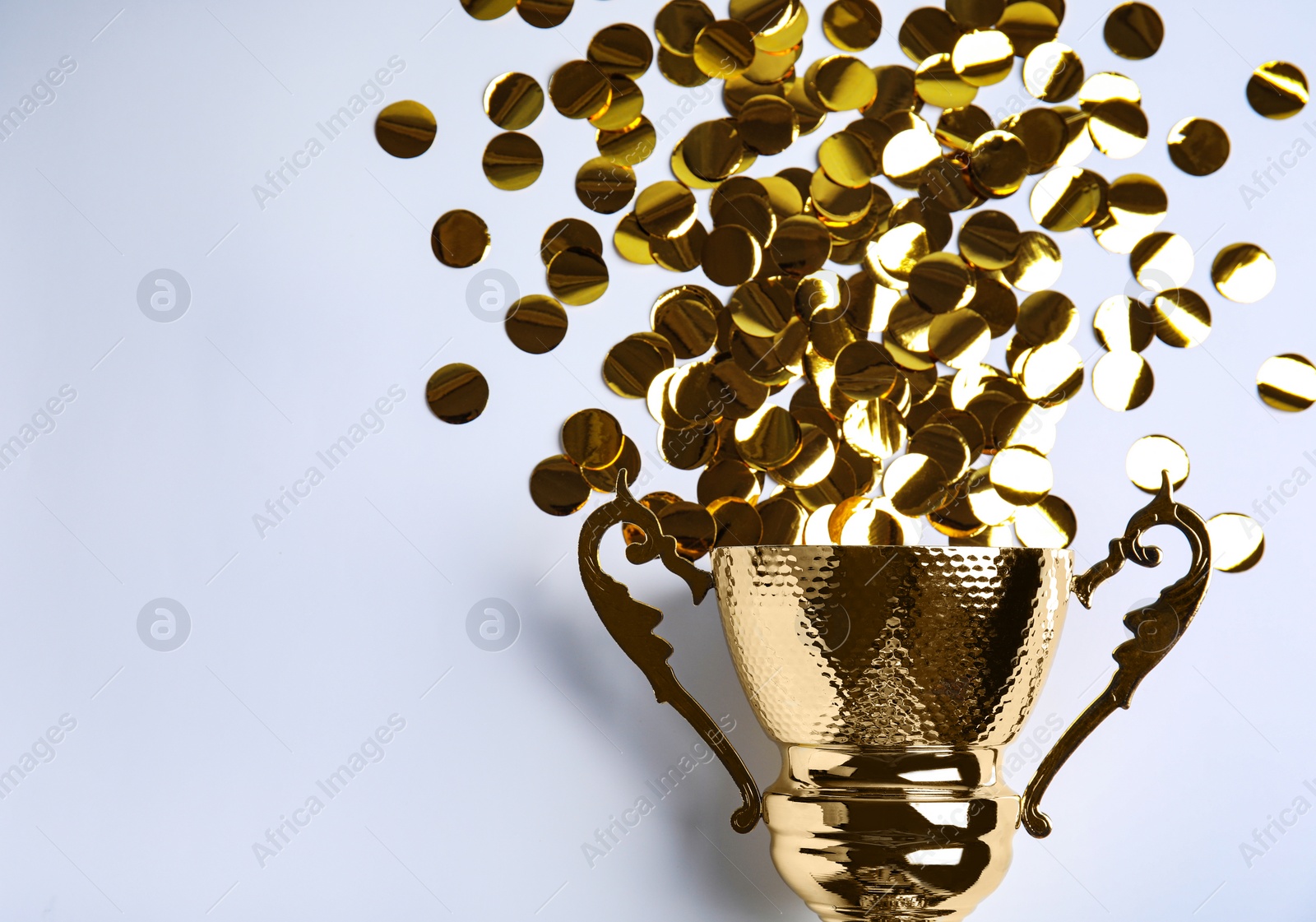 Photo of Gold trophy cup and confetti on white background, top view