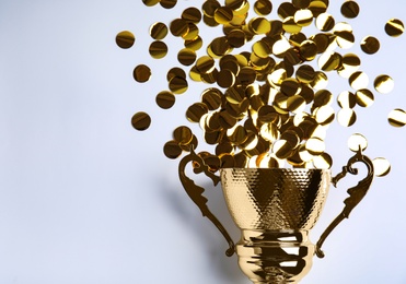 Gold trophy cup and confetti on white background, top view