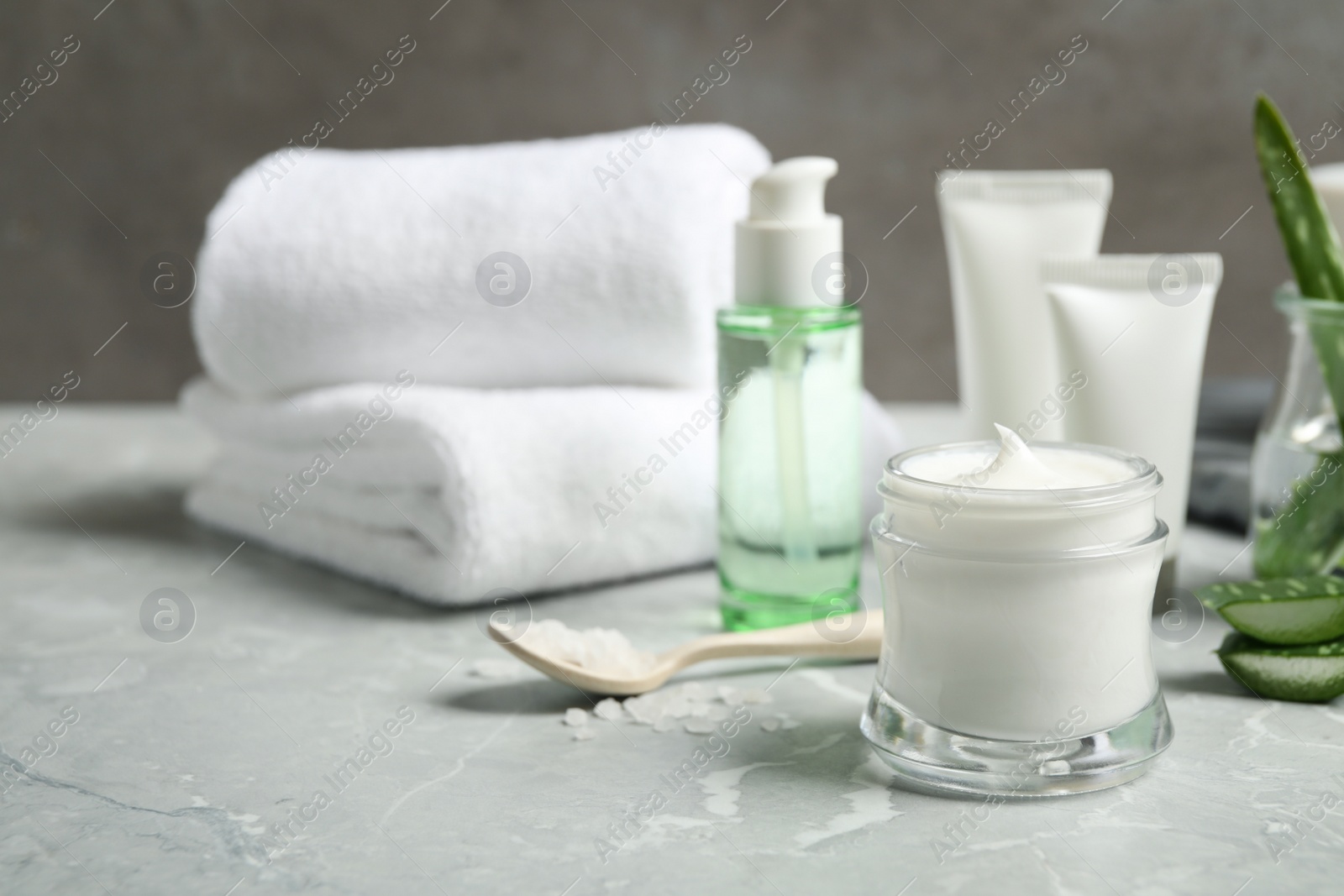 Photo of Different cosmetic products and aloe on grey marble table