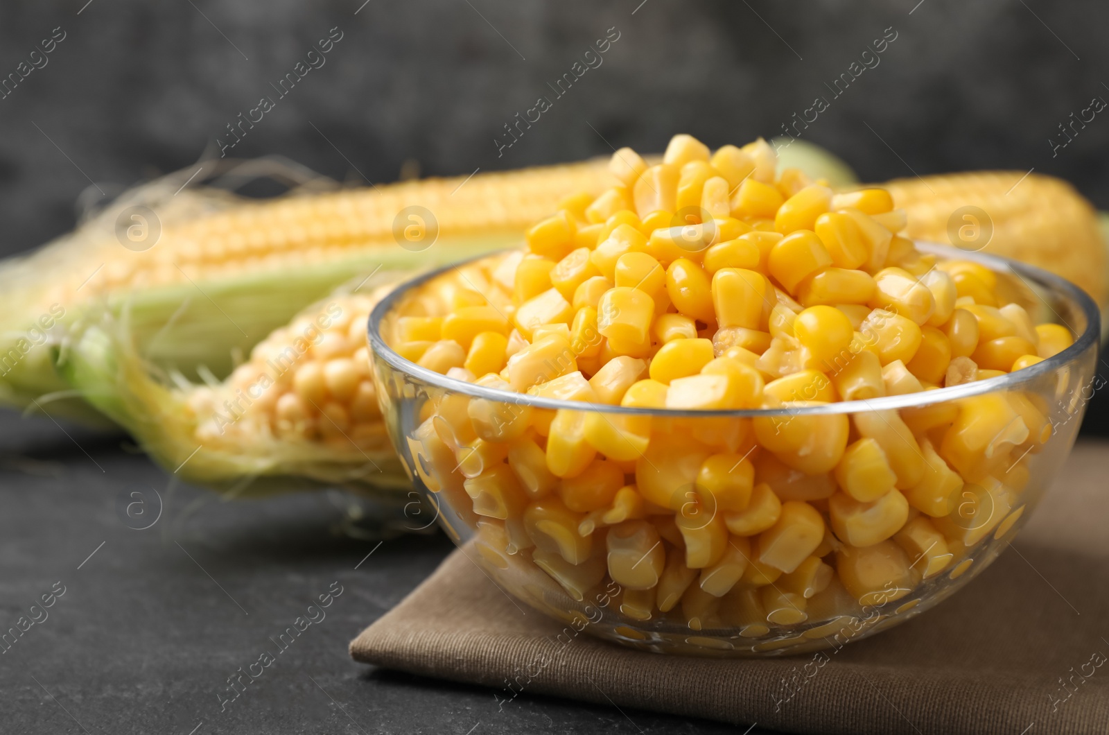 Photo of Bowl of preserved corn on grey table, closeup