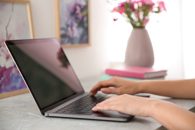 Photo of Woman working with modern laptop at light table, closeup