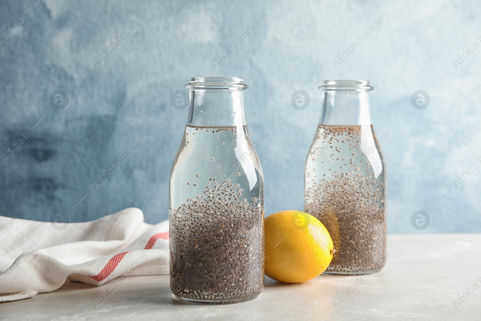 Photo of Composition with bottles of water and chia seeds on table against color background