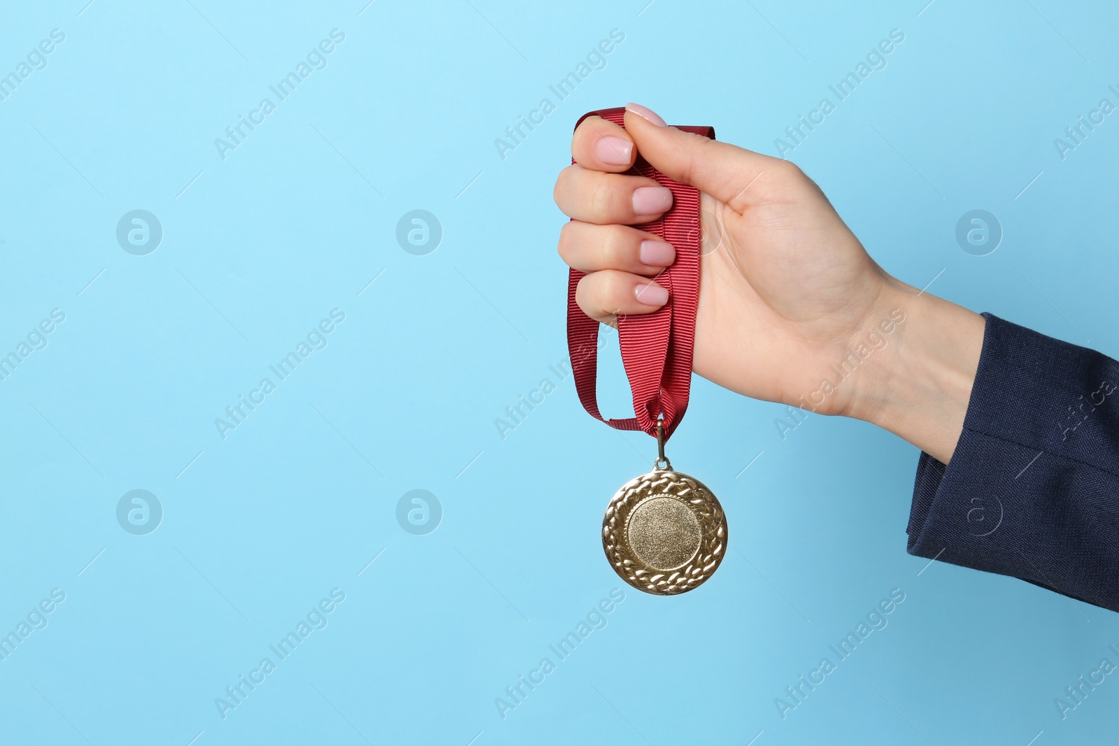 Photo of Woman holding golden medal on color background, closeup. Space for text