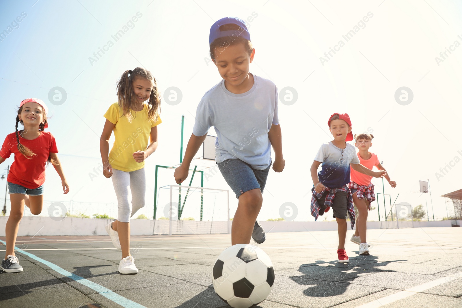 Photo of Cute children playing soccer outdoors on sunny day. Summer camp