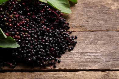 Photo of Pile of tasty elderberries (Sambucus) on wooden table, space for text