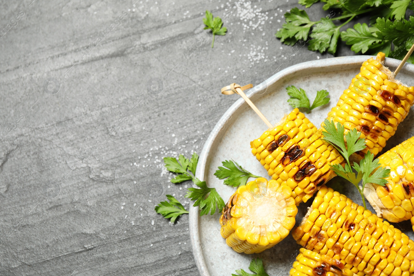 Photo of Delicious grilled corn cobs on grey table, flat lay. Space for text