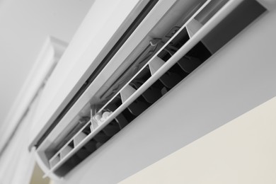 Modern air conditioner on white wall indoors, closeup view