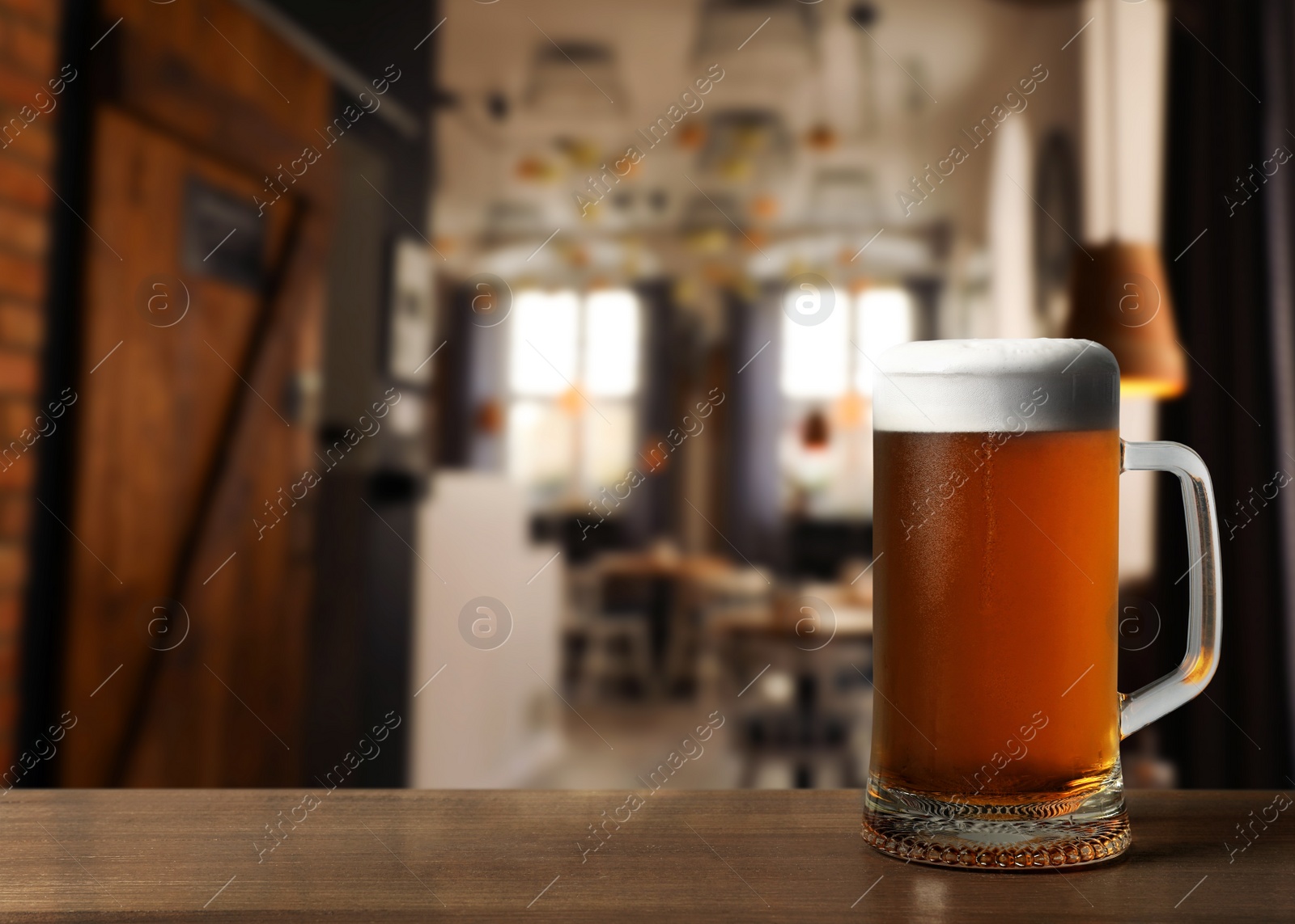 Image of Glass mug with cold tasty beer on wooden table in pub, space for text