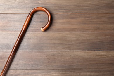 Walking cane on wooden background, top view. Space for text