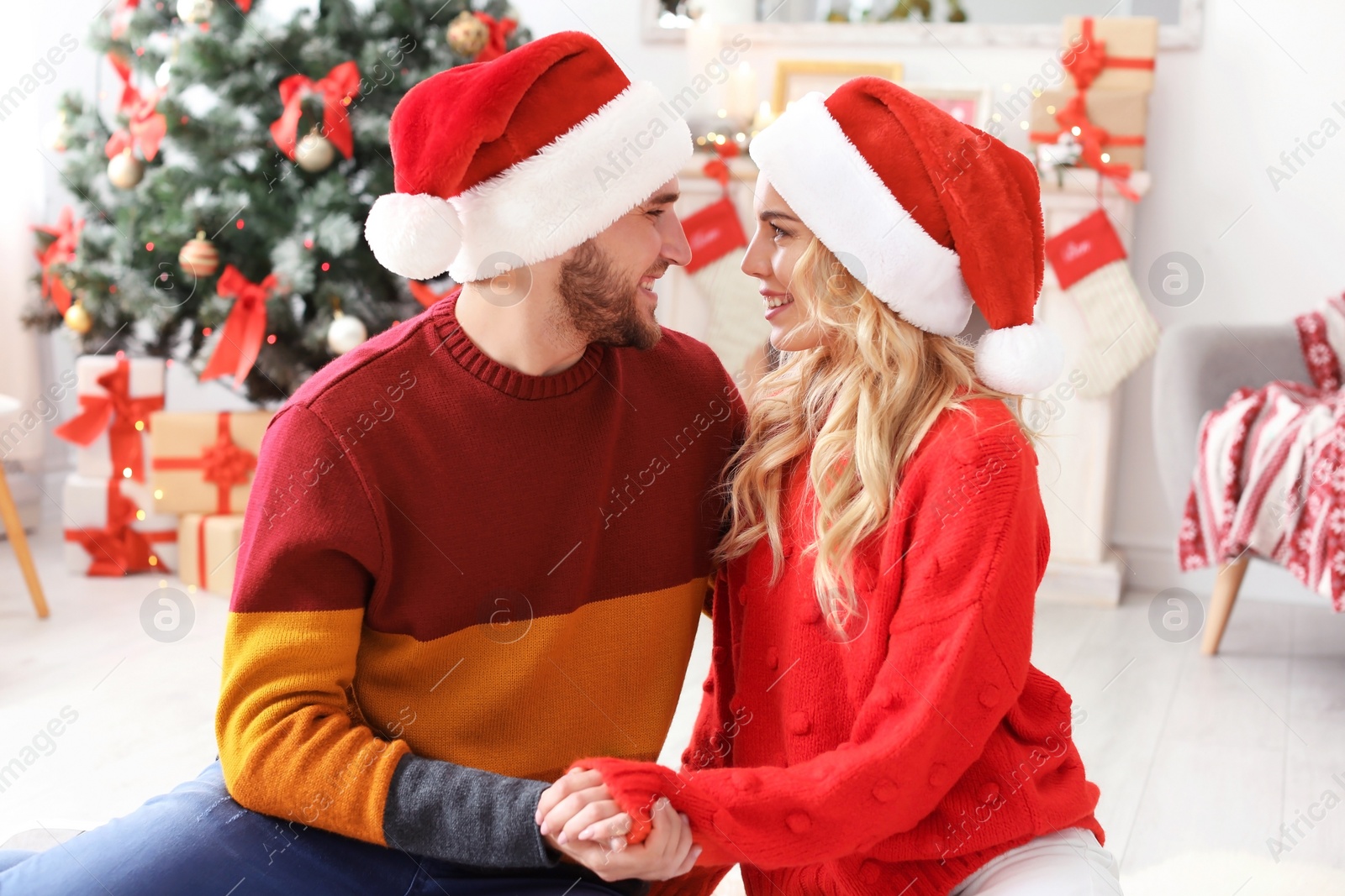 Photo of Young couple in Santa hats at home. Christmas celebration