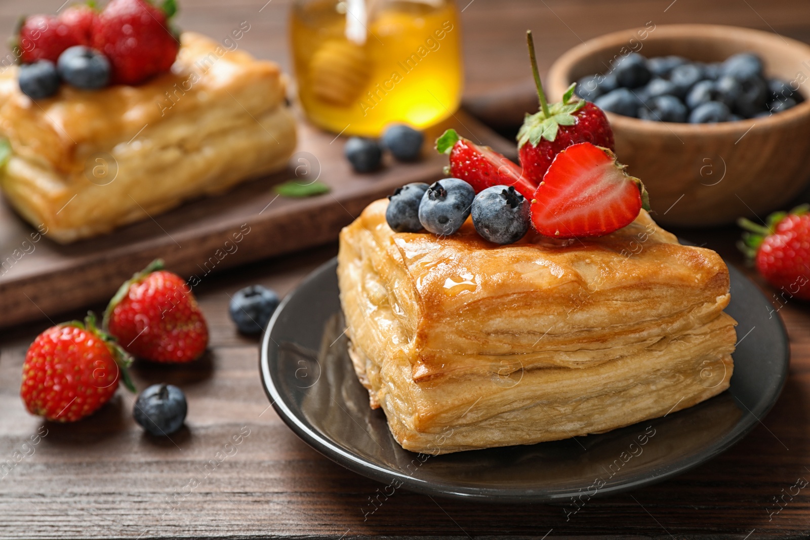 Photo of Fresh delicious puff pastry with sweet berries on wooden table
