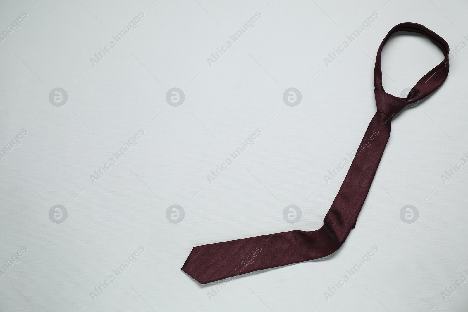 Photo of Brown necktie on light background, top view. Space for text