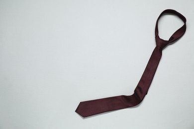 Photo of Brown necktie on light background, top view. Space for text