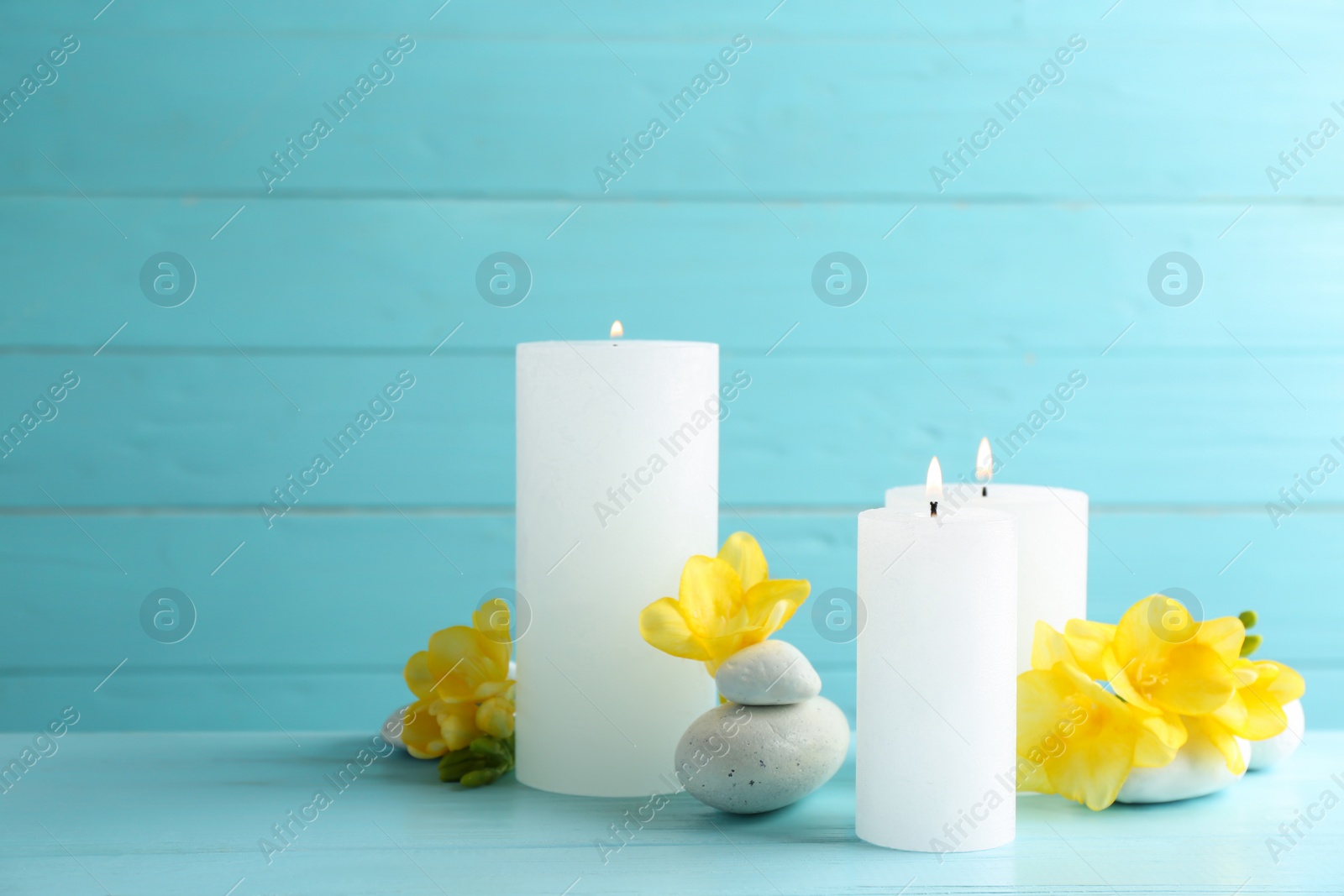 Photo of Composition of burning candles, spa stones and flowers on table. Space for text