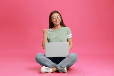 Young woman with modern laptop on pink background