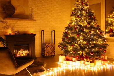Beautiful Christmas tree with festive lights near fireplace in room. Interior design