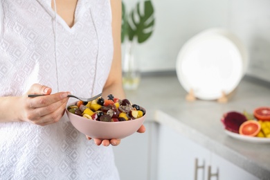 Woman with delicious exotic fruit salad in kitchen, closeup