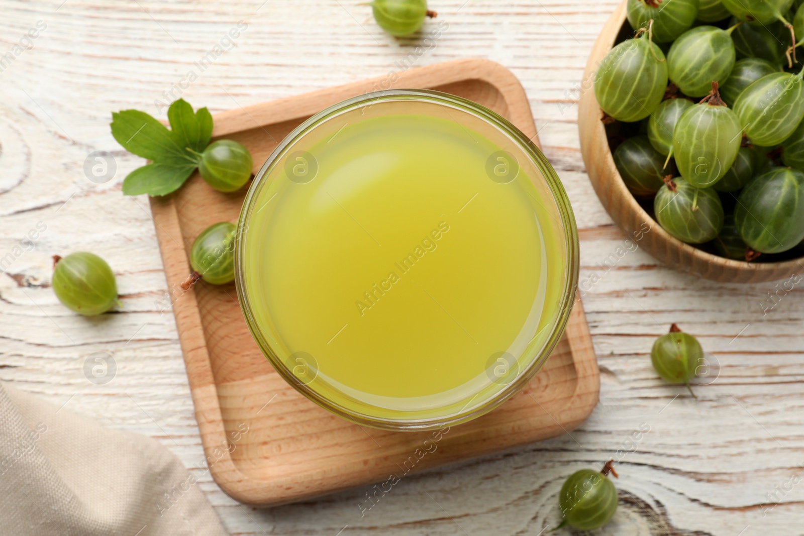 Photo of Tasty gooseberry juice and fresh berries on white wooden table, flat lay