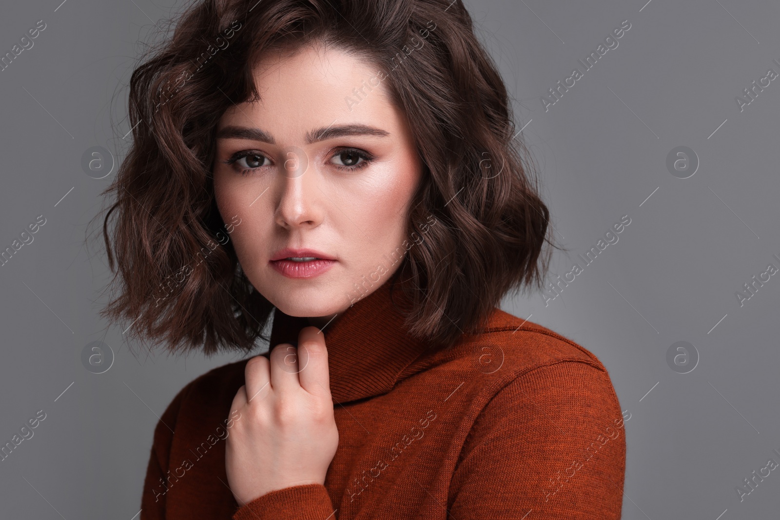 Photo of Portrait of beautiful young woman with wavy hairstyle on grey background