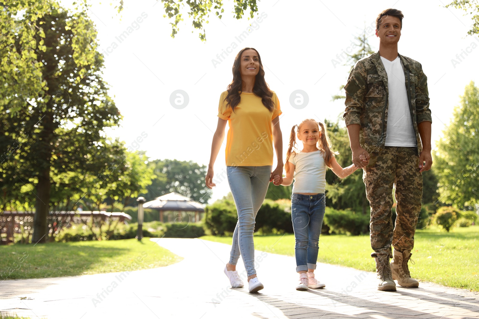 Photo of Man in military uniform and his family walking at sunny park