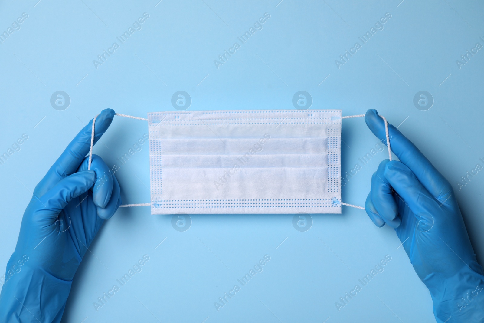 Photo of Doctor with protective mask on light blue background, top view. Safety equipment